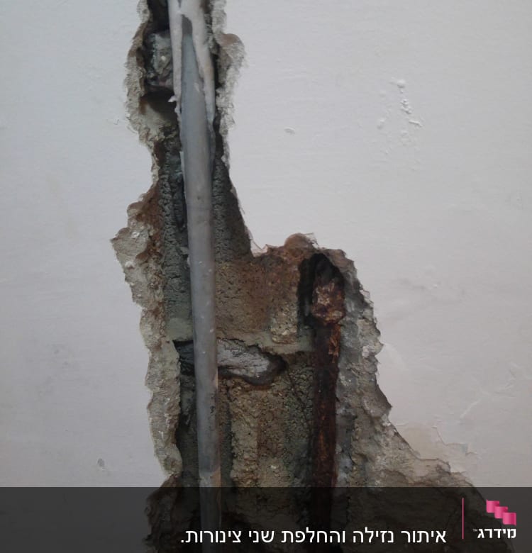 צינור מים חשוף בקיר שבור עם חלודה